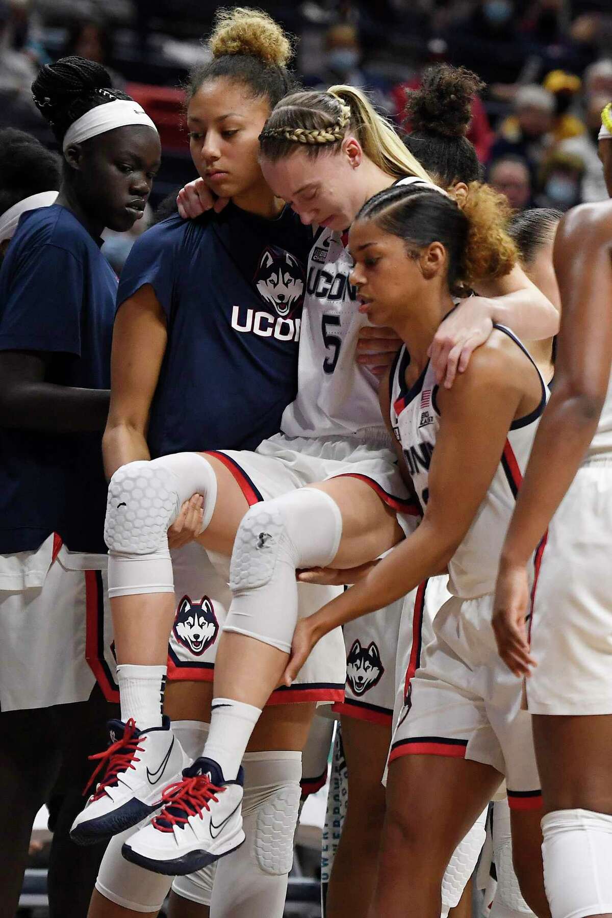 Connecticut's Paige Bueckers, center, is helped off the court by Amari DeBerry, left, and Evina Westbrook in the second half of an NCAA college basketball game against Notre Dame, Sunday, Dec. 5, 2021, in Storrs.