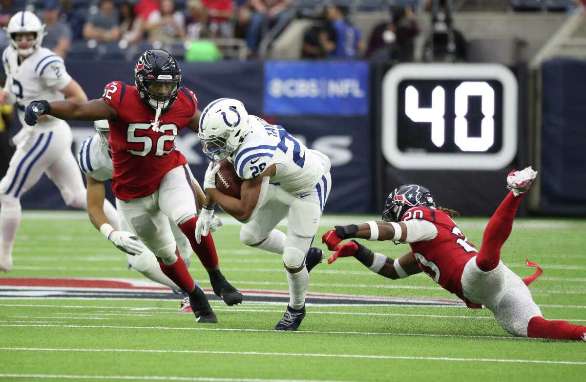 Indianapolis Colts running back Jonathan Taylor (28) gains yardage against Houston Texans defensive end Jonathan Greenard (52) and safety Justin Reid (20) during the first half of an NFL football game at NRG Stadium, Sunday, Dec. 5, 2021 in Houston.