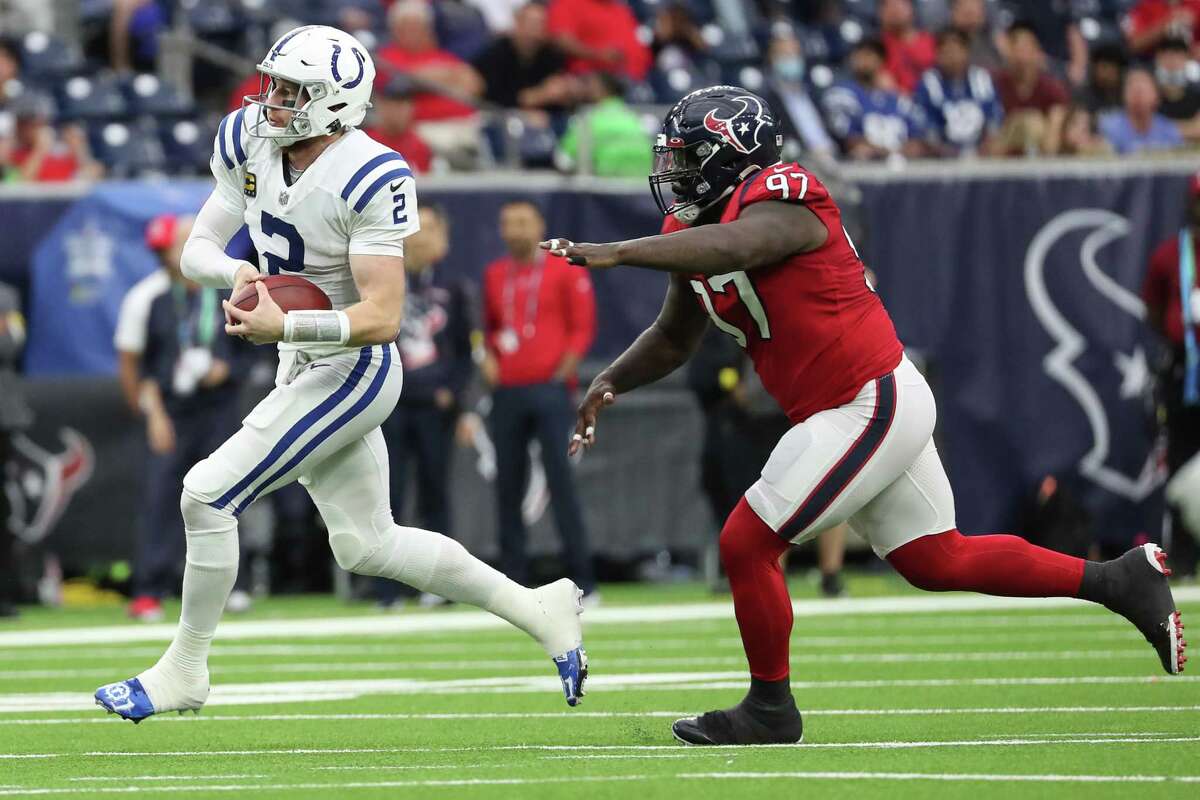 Indianapolis Colts quarterback Carson Wentz (2) races out of the pocket, chased by Houston Texans defensive tackle Maliek Collins (97), for a first down during the second quarter of an NFL football game Sunday, Dec. 5, 2021 in Houston.