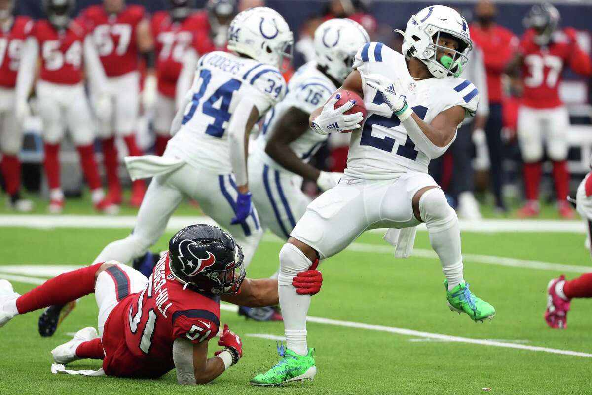 Indianapolis Colts running back Nyheim Hines (21) is tripped up by Houston Texans outside linebacker Kamu Grugier-Hill (51) as he returns a punt during the first half of an NFL football game Sunday, Dec. 5, 2021 in Houston.