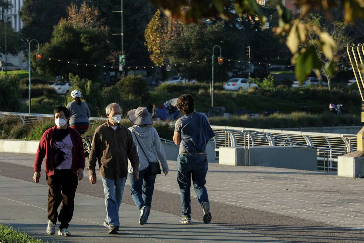 蒙面行人在奥克兰的梅里特湖附近散步。这种omicron变种导致加州的冠状病毒病例达到创纪录的激增。