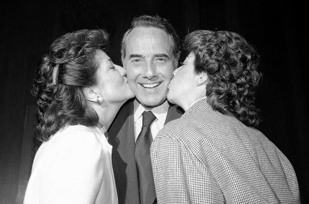 FILE - In this Nov. 28, 1984, file photo, newly elected Senate Majority Leader Dole, of Kansas, is kissed by his wife, Transportation Secretary Elizabeth Dole and his daughter, Robin, on Capitol Hill in Washington. Bob Dole, who overcame disabling war wounds to become a sharp-tongued Senate leader from Kansas, a Republican presidential candidate and then a symbol and celebrant of his dwindling generation of World War II veterans, has died. He was 98. His wife, Elizabeth Dole, posted the announcement Sunday, Dec. 5, 2021, on Twitter. (AP Photo/Ira Schwarz, File)