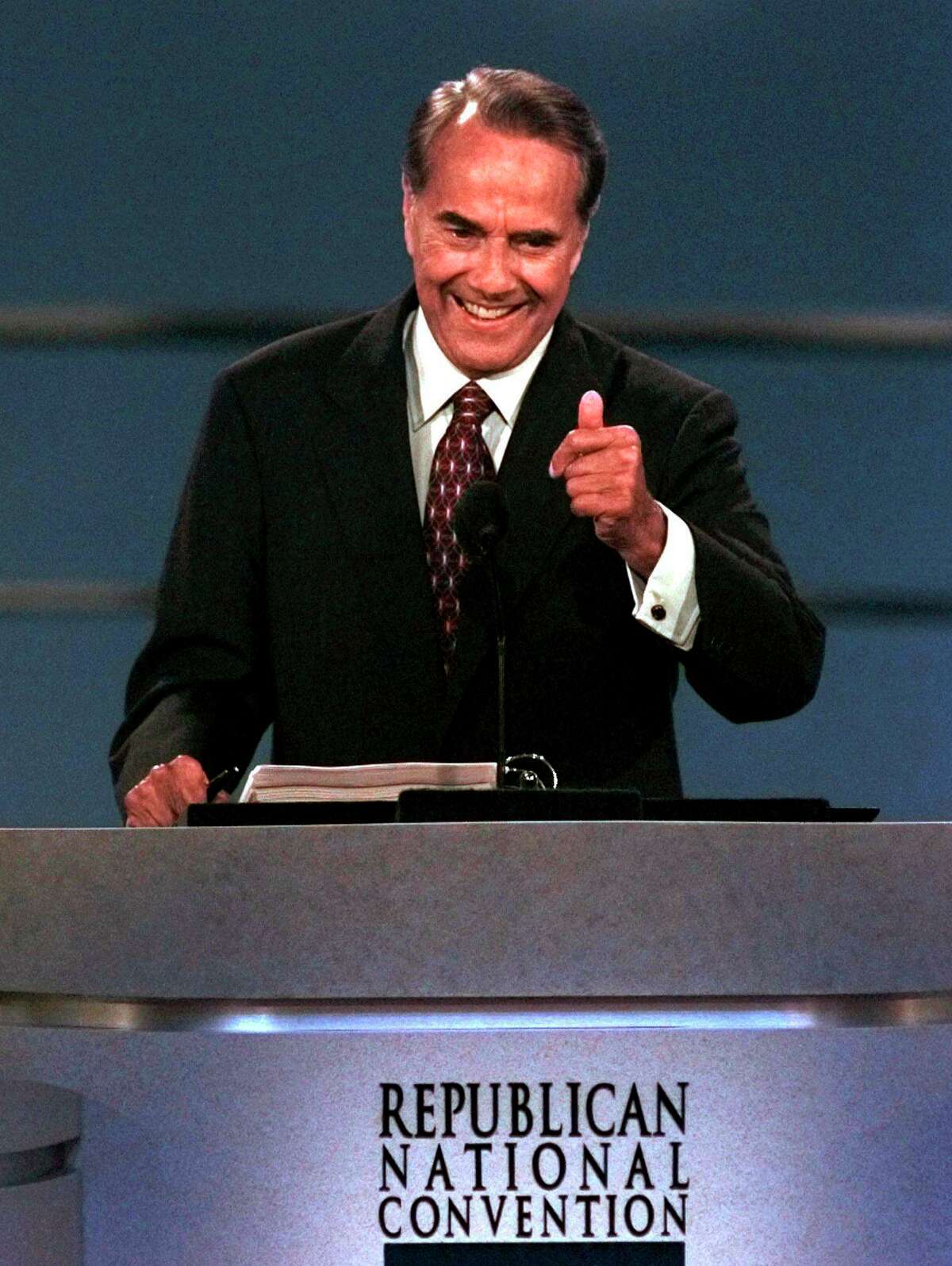 FILE - Republican presidential nominee Bob Dole stands before the Republican National Convention, in San Diego, Aug. 15, 1996. Offering himself as a man tested by adversity, made sensitive by hardship, Dole accepted the Republican presidential nomination Thursday night with a scorching indictment of the Clinton administration and vowing a return to heartland values of faith and trust. (AP Photo/Ron Edmonds, File)