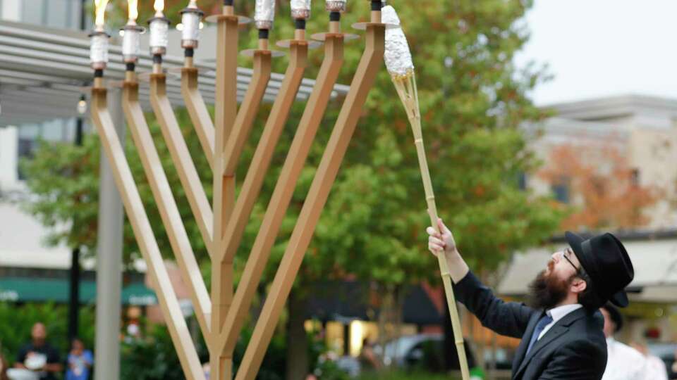 Rabbi Mendel Blecher lights a nine-foot menorah during the annual lighting to celebrate Hanukkah at Market Street, Sunday, Dec. 5, 2021, in The Woodlands. For the last decade, Chabad of The Woodlands has held the event in celebrate the Jewish holiday tradition as a community-wide celebration.