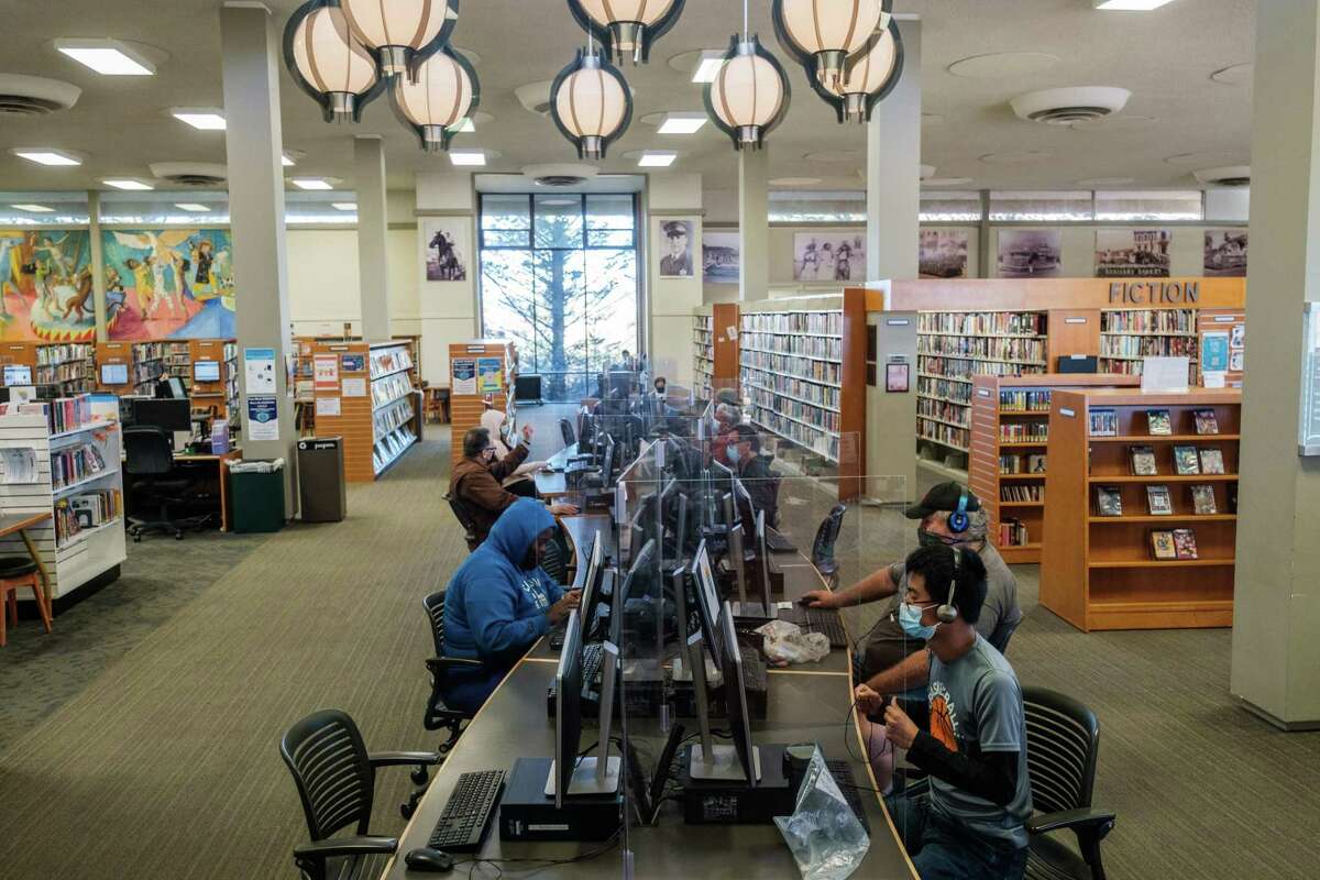 人们在南旧金山公共图书馆使用计算机站。一项联邦拨款为图书馆提供软件，以便求职者可以参加在线课程和练习考试。