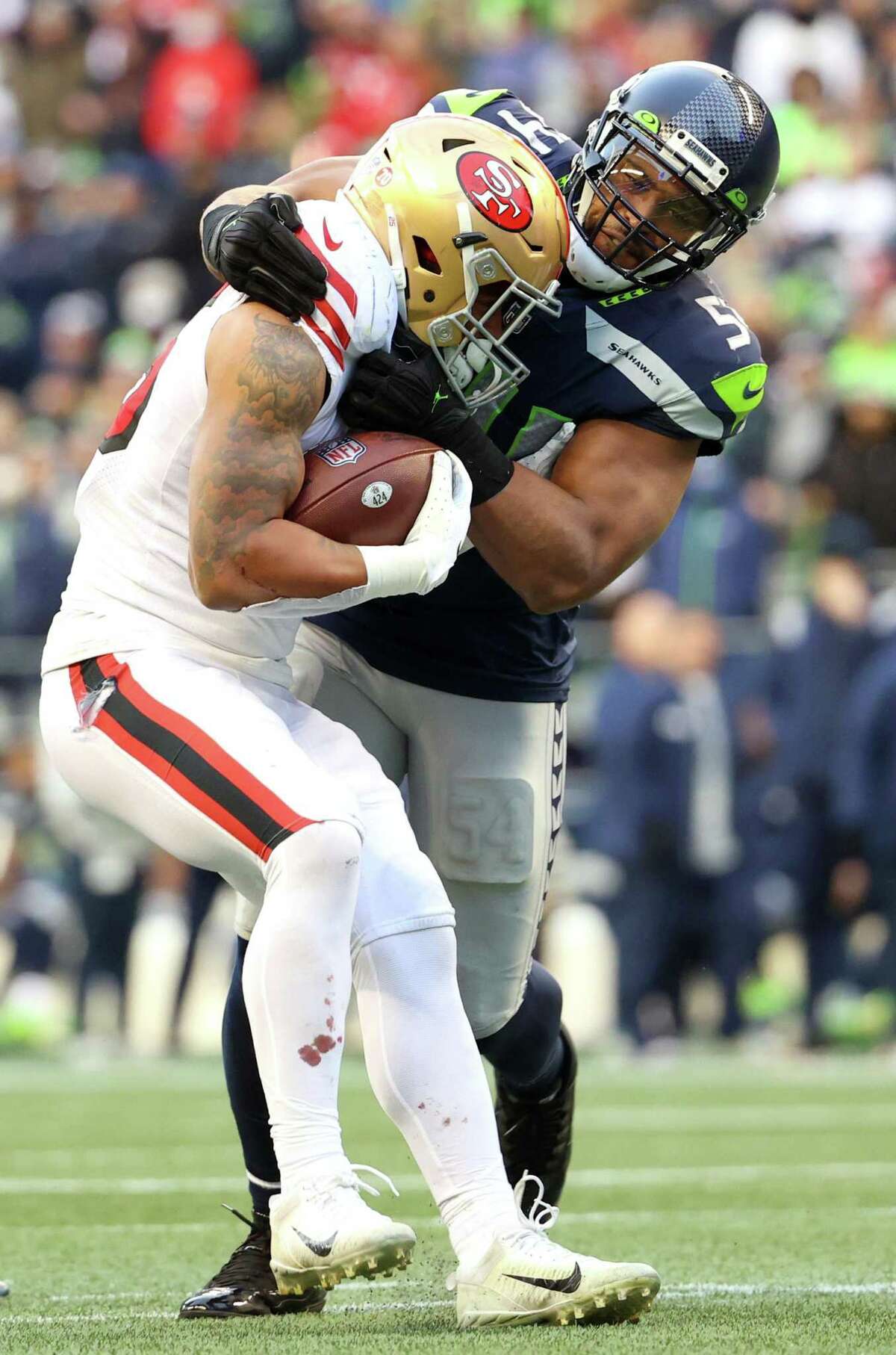 SEATTLE, WASHINGTON - DECEMBER 05: Eli Mitchell #25 of the San Francisco 49ers is tackled by Bobby Wagner #54 of the Seattle Seahawks during the third quarter at Lumen Field on December 05, 2021 in Seattle, Washington. (Photo by Abbie Parr/Getty Images)