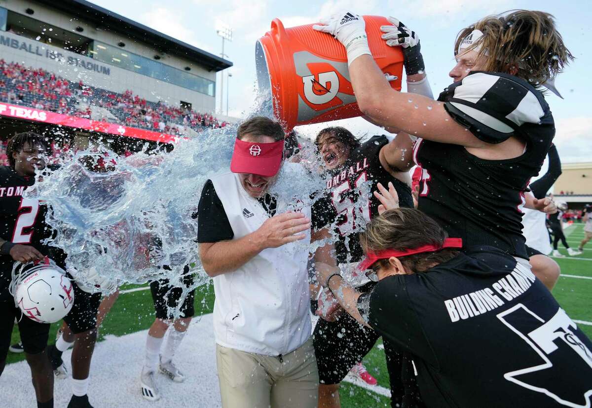 Tomball head coach Kevin Flanagan, left, is doused with liquid by Jaden O’Bryan (51) and Travis Bates, right, after the team’s win over Bridgeland in the 6A Division II Region 3 Final high school football playoff game, Saturday, Dec. 4, 2021, in Tomball.