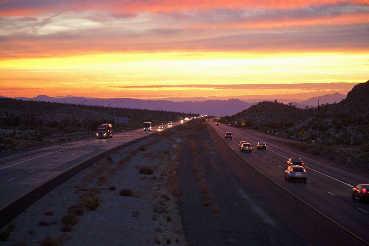 Cars drive Interstate 15 at sunset at the California-Nevada border looking west.