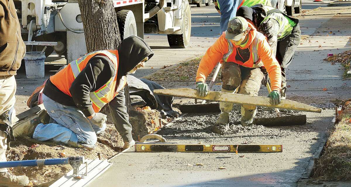 John Badman|The Telegraph Workers from Stutz Excavating were smoothing a fresh pour of concrete Monday in the 300 block of East Acton Avenue in Wood River. Bad sections of the sidewalk on the street are being replaced, along with corner sections at each side street to make them ADA compliant.