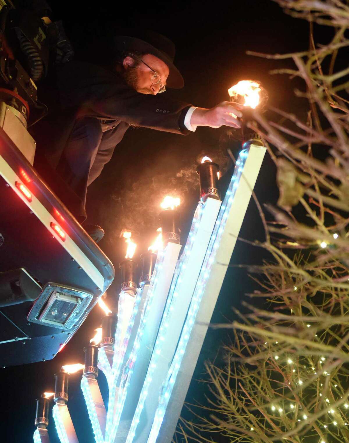 Rabbi Yossi Deren lights the giant menorah at the Chabad Lubavitch of Greenwich parade and community menorah lighting in downtown Greenwich, Conn. Sunday, Dec. 5, 2021. Folks paraded from Cos Cob School to central Greenwich to celebrate Hanukkah and light a large menorah at the intersection of Arch Street and Greenwich Avenue.