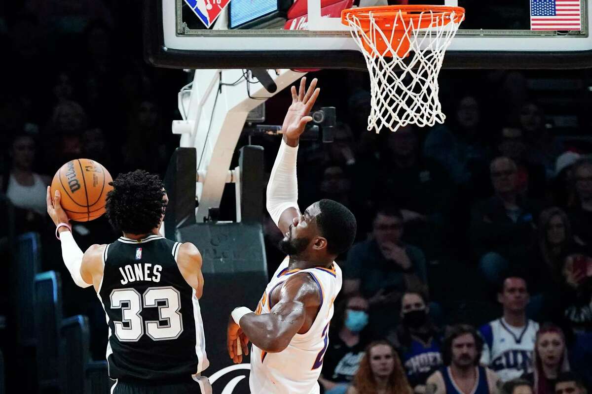 Phoenix Suns center Deandre Ayton, right, jumps up to block a shot by San Antonio Spurs guard Tre Jones (33) during the second half of an NBA basketball game Monday, Dec. 6, 2021, in Phoenix. (AP Photo/Ross D. Franklin)
