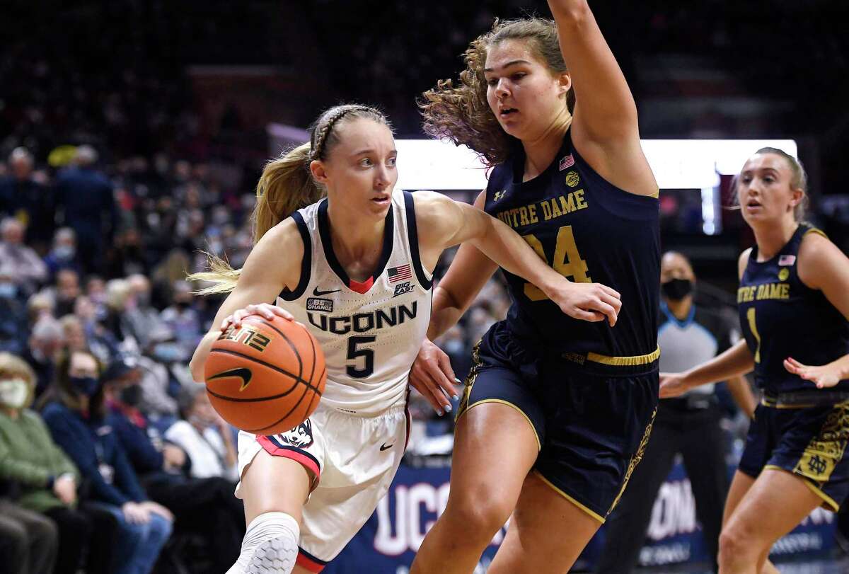 Connecticut's Paige Bueckers dribbles around Notre Dame's Madelyn Westbeld (34) in the first half of an NCAA college basketball game, Sunday, Dec. 5, 2021, in Storrs, Conn. (AP Photo/Jessica Hill)