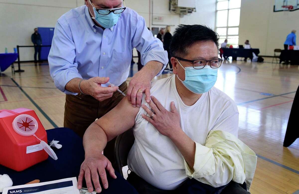 Jerry Eng receives his vaccination dose from Dr. Jose Cara during the Darien booster clinic Tuesday, December 7, 2021 at Town Hall in Darien, Conn. The town is currently experiencing a surge in COVID cases and officials are asking everyone to stay vigilant.