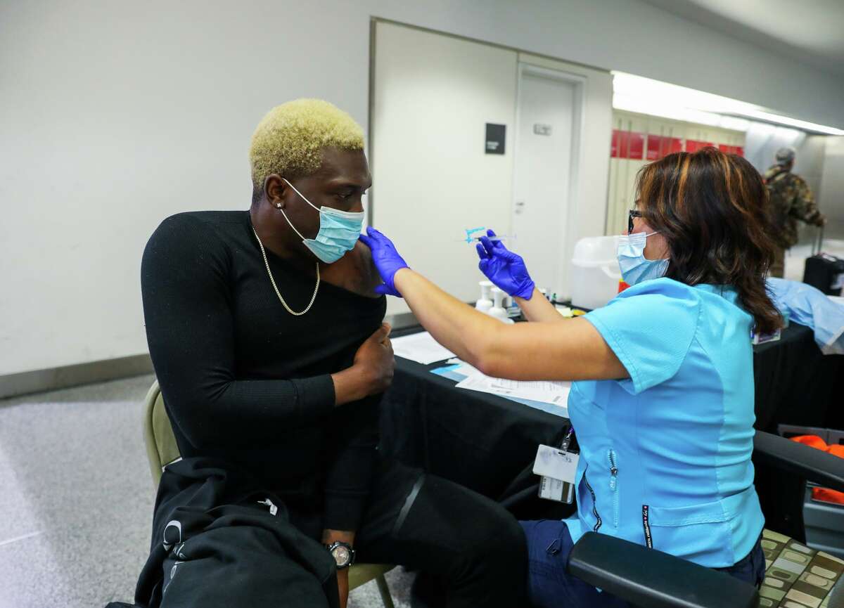 Quintyne Lawrence, 32, of San Francisco receives a Johnson and Johnson vaccine from Jojie Gooselaw, a registered nurse, at the SFO Medical Clinic at San Francisco International Airport on Tuesday. Demand for vaccines is rising as concerns over the omicron variant grow.