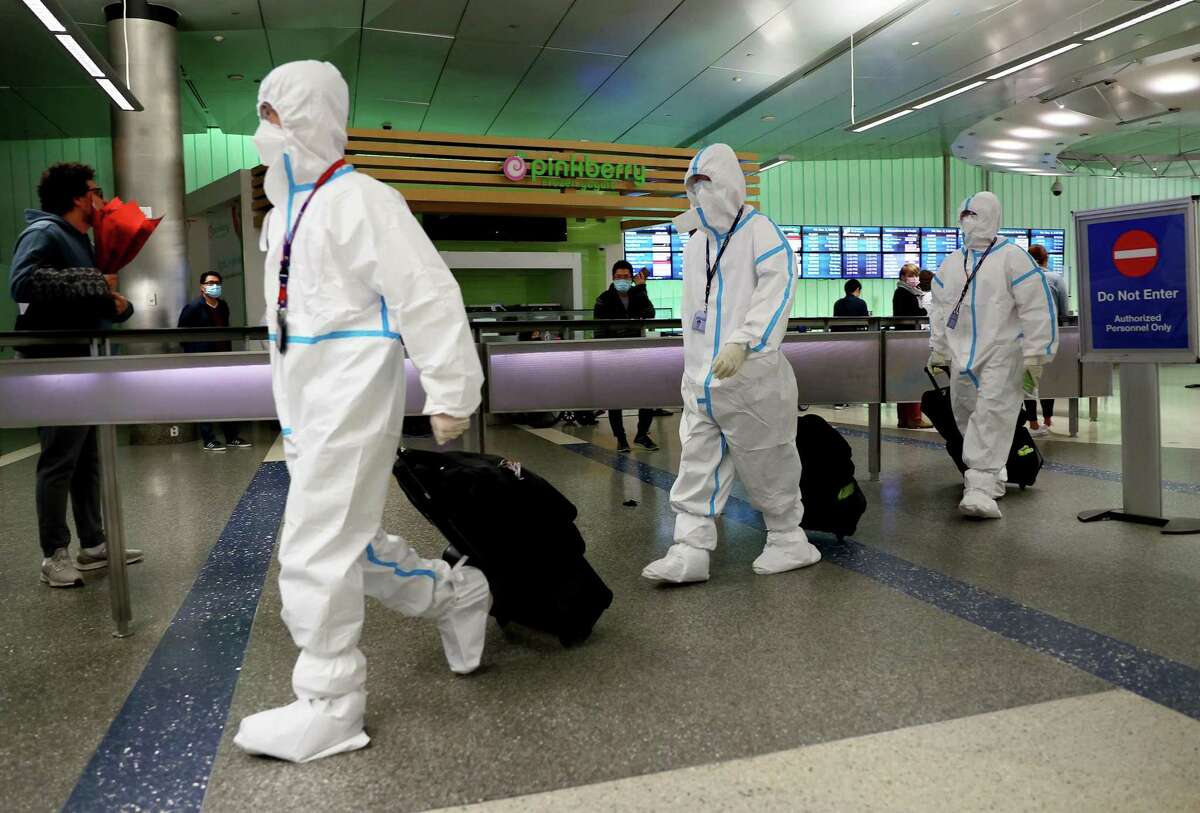 Air China flight crew members wear protective suits as they arrive in the international terminal at Los Angeles International Airport on Friday. The omicron variant has sparked global concern and is spreading in California and around the world.