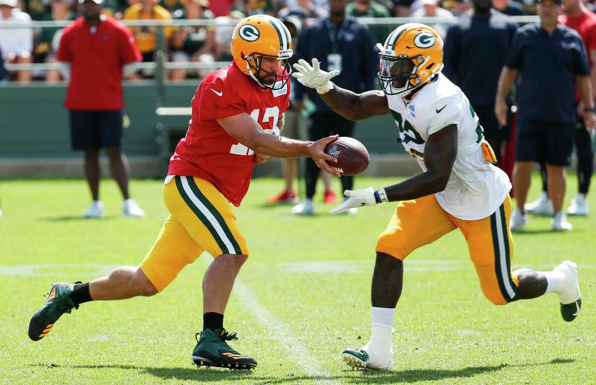 Green Bay Packers quarterback Aaron Rodgers hands the ball off to running back Dexter Williams during a joint 2019 training camp practice with the Houston Texans.