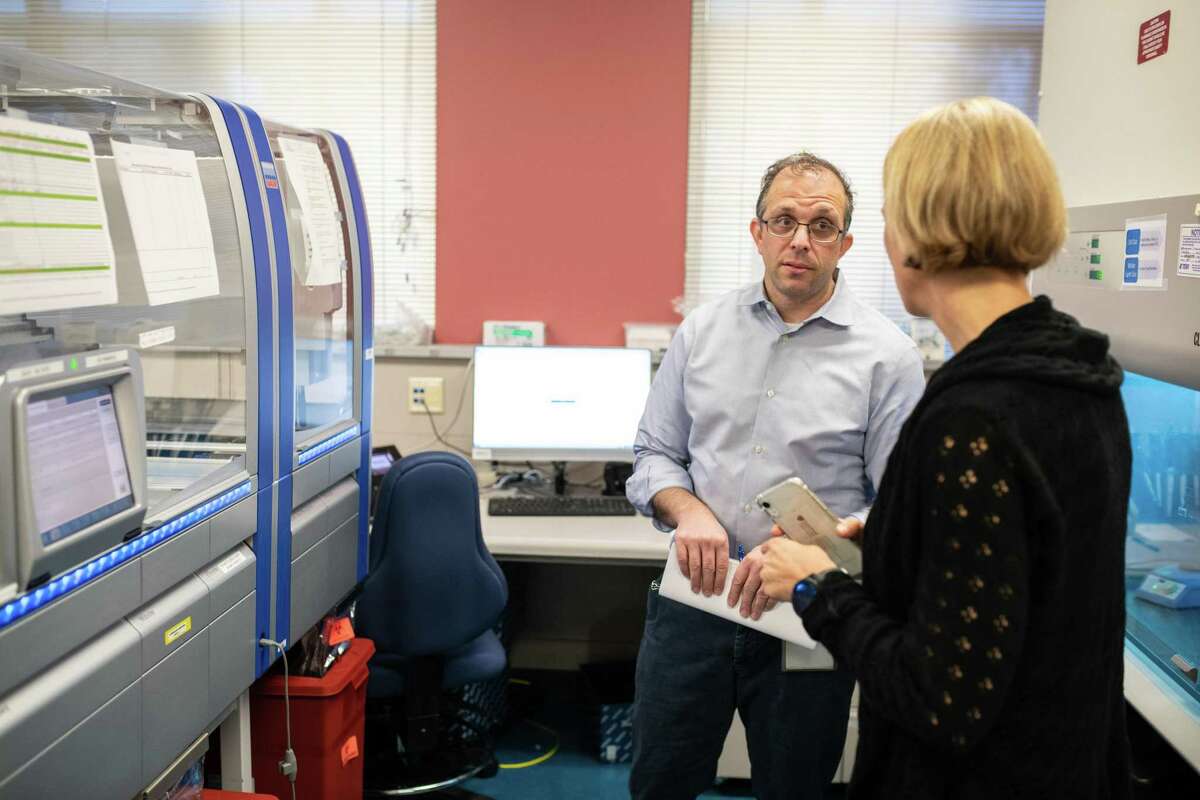 2021年12月，斯坦福临床病毒学实验室医学主任本杰明·平斯基博士在用于冠状病毒基因组测序的设备前与同事交谈。