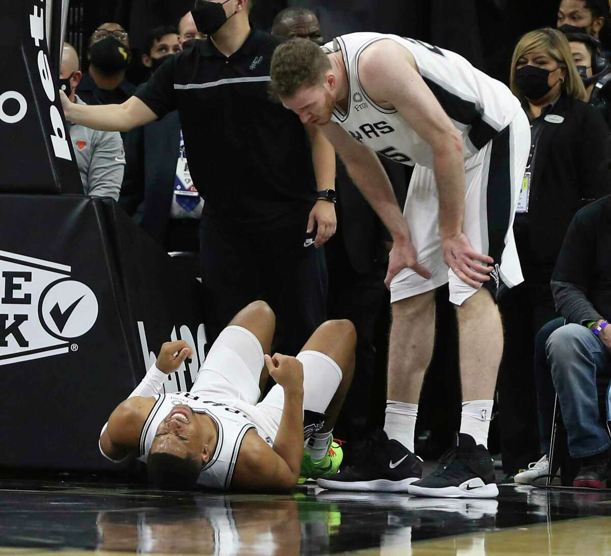 The Spurs’ Keldon Johnson (3) lies on the court in apparent pain as teammate Jakob Poeltl checks on him near the end of the first half against the New York Knicks at the AT&T Center on Tuesday, Dec. 7, 2021.