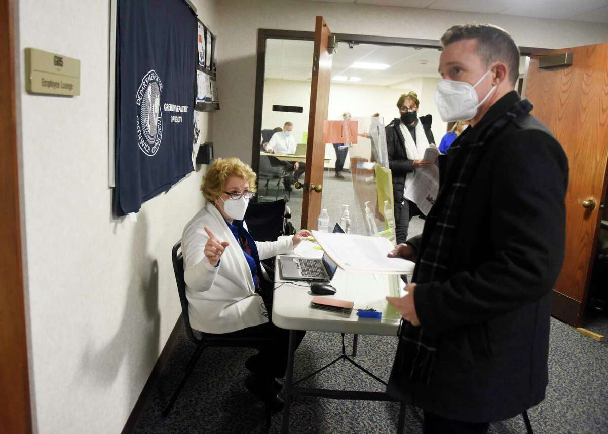 Stamford's Dan Venette checks in with town employee Linda Conti at the COVID-19 booster clinic at Town Hall in Greenwich, Conn. Wednesday, Dec. 8, 2021. Greenwich Hospital identified two cases of omicron variant of COVID-19 Wednesday, but both cases were mild and did not require hospitalization.