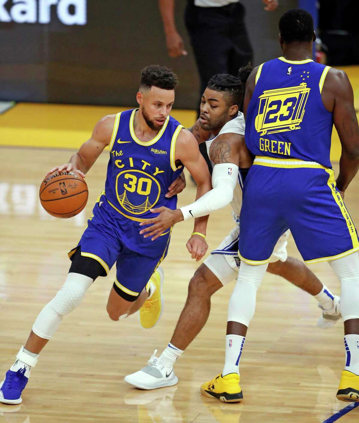 Golden State Warriors' Stephen Curry dribbles as Draymond Green screens Orlando Magic's Frank Mason III in 1st quarter during NBA game at Chase Center in San Francisco, Calif., on Thursday, February 11, 2021.