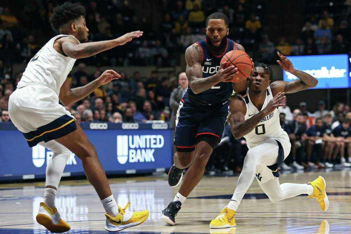 UConn guard R.J. Cole, center, is defended by West Virginia guards Taz Sherman, left, and Kedrian Johnson (0) during the first half in Morgantown, W.Va., on Wednesday. The Mountaineers won 56-53.