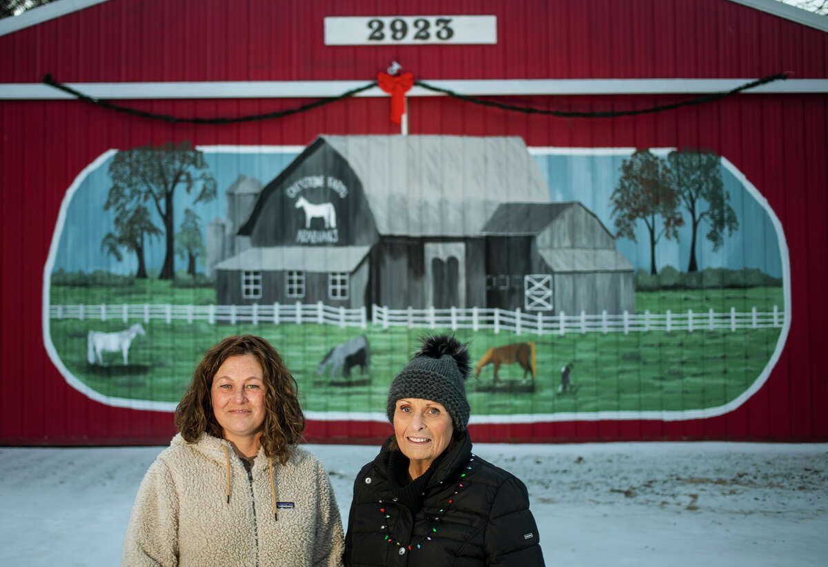 Linda Dice, right, and Amy Mudd, left, pose for a portrait Tuesday, Dec. 7, 2021 in front of the mural Mudd created on a large barn on Dice's property, adding to the family's Christmas display.