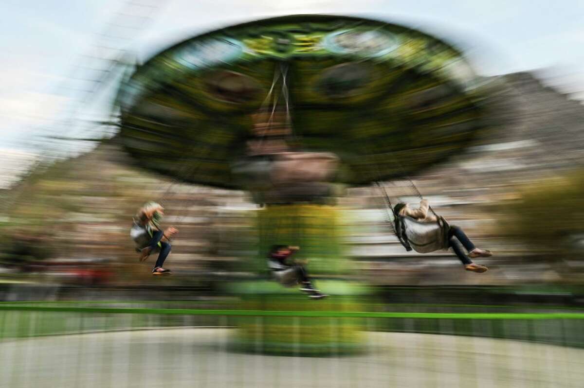 Youths enjoy a merry-go-round ride at an amusement park. (Photo by Hector Retamal/AFP via Getty Images)