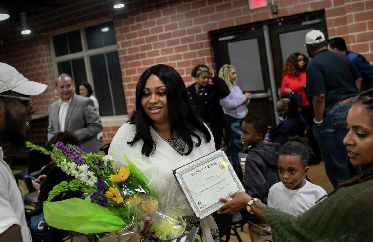 Tia Rodriguez of Urban Soul, a vegan soul food restaurant, smiles as she holds her program diploma and flowers during the Embracing Entrepreneurial Equity program graduation at the Maestro Entrepreneur Center in San Antonio on Wednesday.
