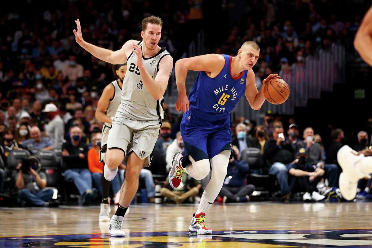 DENVER, CO - OCTOBER 22: Nikola Jokic #15 of the Denver Nuggets dribbles past Jakob Poeltl #25 of the San Antonio Spurs at Ball Arena on October 22, 2021 in Denver, Colorado. NOTE TO USER: User expressly acknowledges and agrees that, by downloading and or using this photograph, User is consenting to the terms and conditions of the Getty Images License Agreement. (Photo by Jamie Schwaberow/Getty Images)
