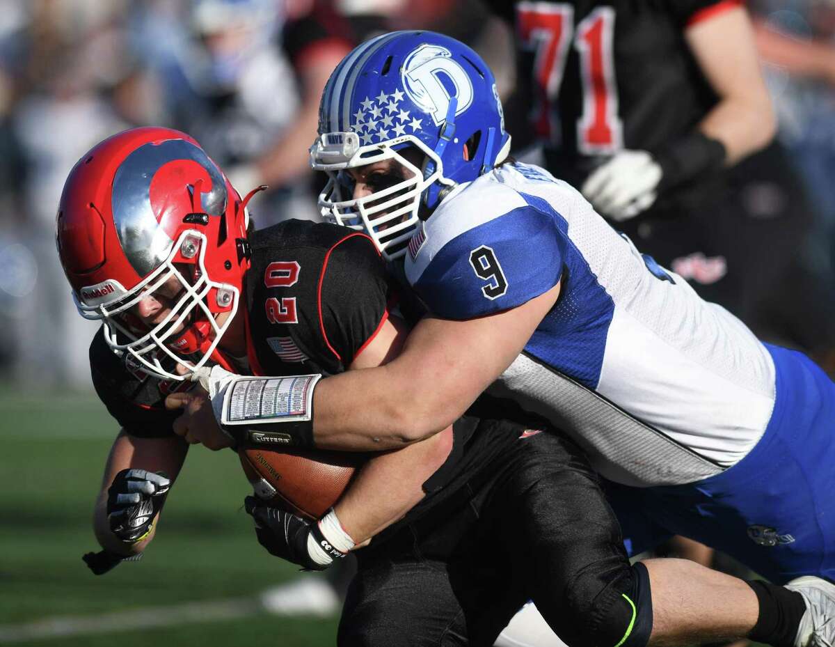 Darien’s David Evanchick (9) tackles New Canaan’s Conor Bailey during a the Class LL semifinals in New Canaan on Sunday.