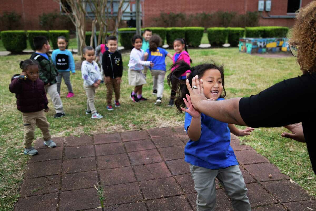 A student runs toward KhaRaven Guevara, chilcare director of AAMA's Early Childhood Center, as they play “red light, green light" in the center’s courtyard, Wednesday, Dec. 8, 2021, in Houston.