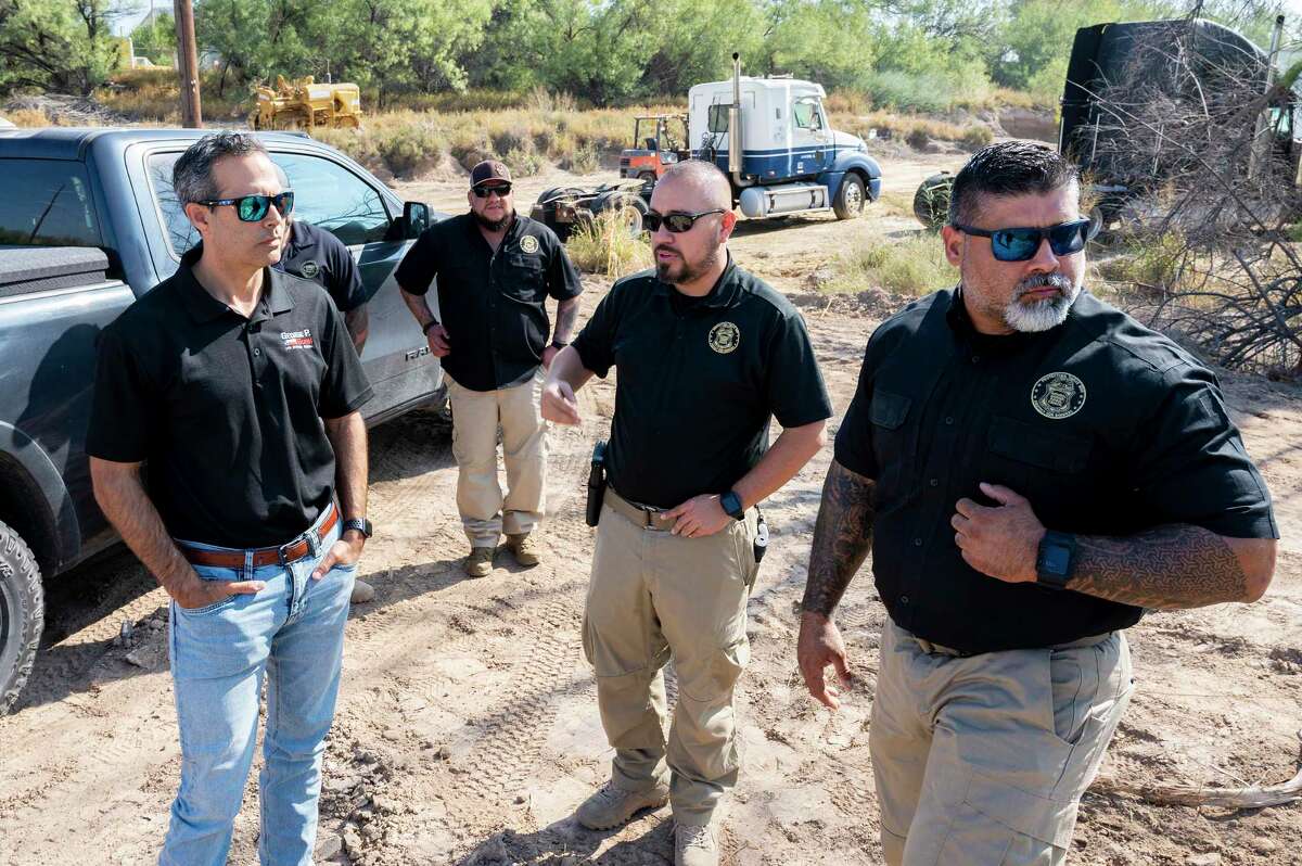 Texas Attorney General candidate George P. Bush listens to National Border Patrol Union Local 2455 members Chris Cabrera and Oscar Vela as they explain how an area is monitored during a visit to a known illegal crossing site behind City Ready Mix as part of a border tour.
