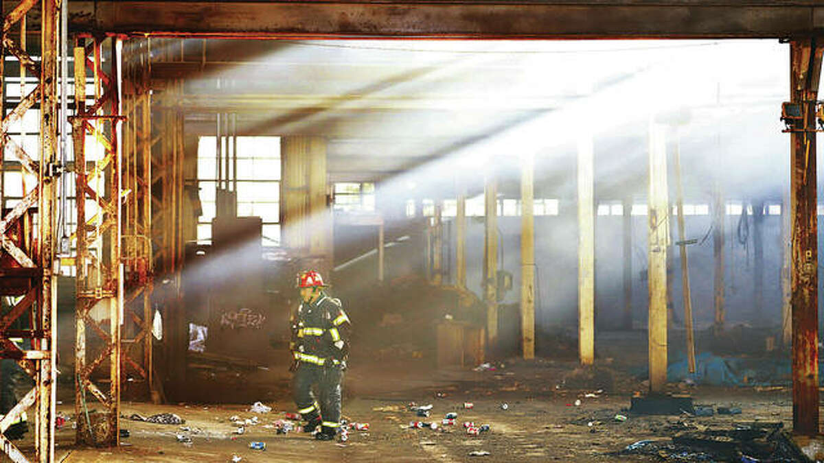 An Alton firefighter walks through the smoke-filled, large and empty metal building Wednesday at 575 Piasa St. in Alton after extinguishing a fire in a barrel.