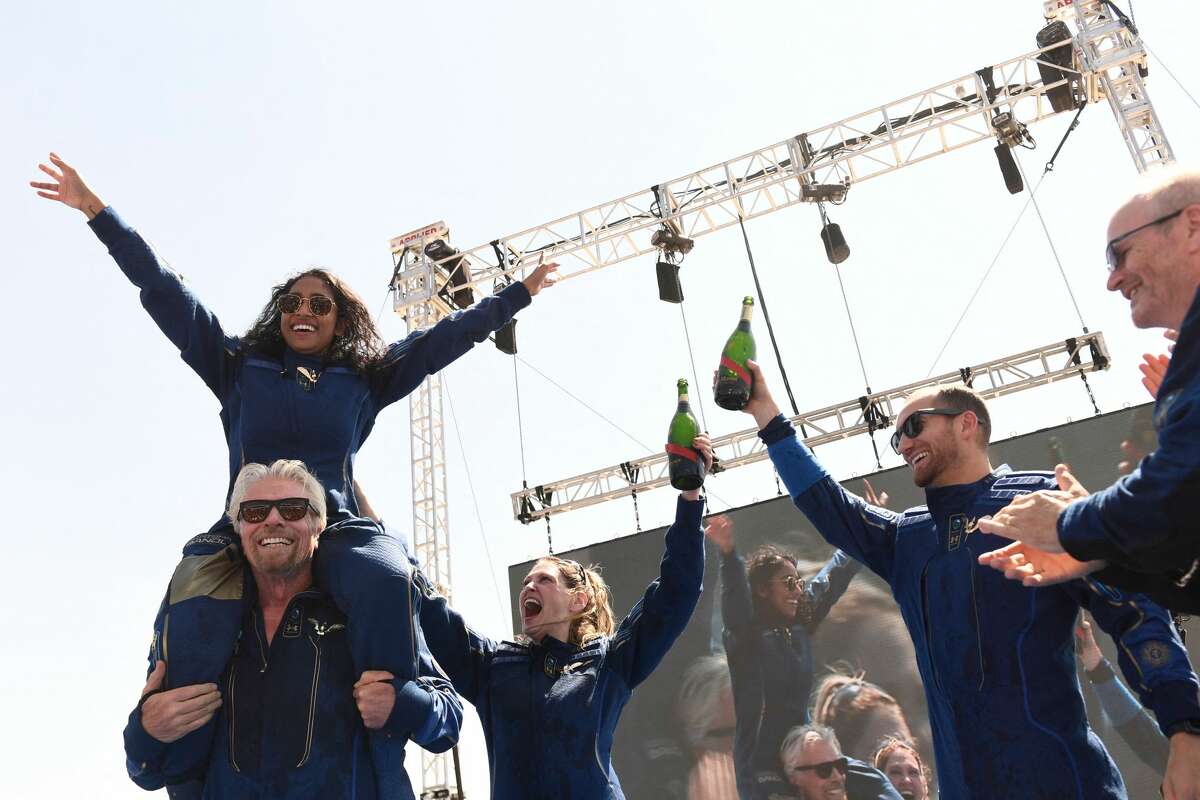 Virgin Galactic founder Sir Richard Branson(L), with Sirisha Bandla on his shoulders, cheers with crew members after flying into space aboard a Virgin Galactic vessel, a voyage he described as the "experience of a lifetime" -- and one he hopes will usher in an era of lucrative space tourism at Spaceport America, near Truth and Consequences, New Mexico on July 11, 2021. (Photo by PATRICK T. FALLON/AFP via Getty Images)