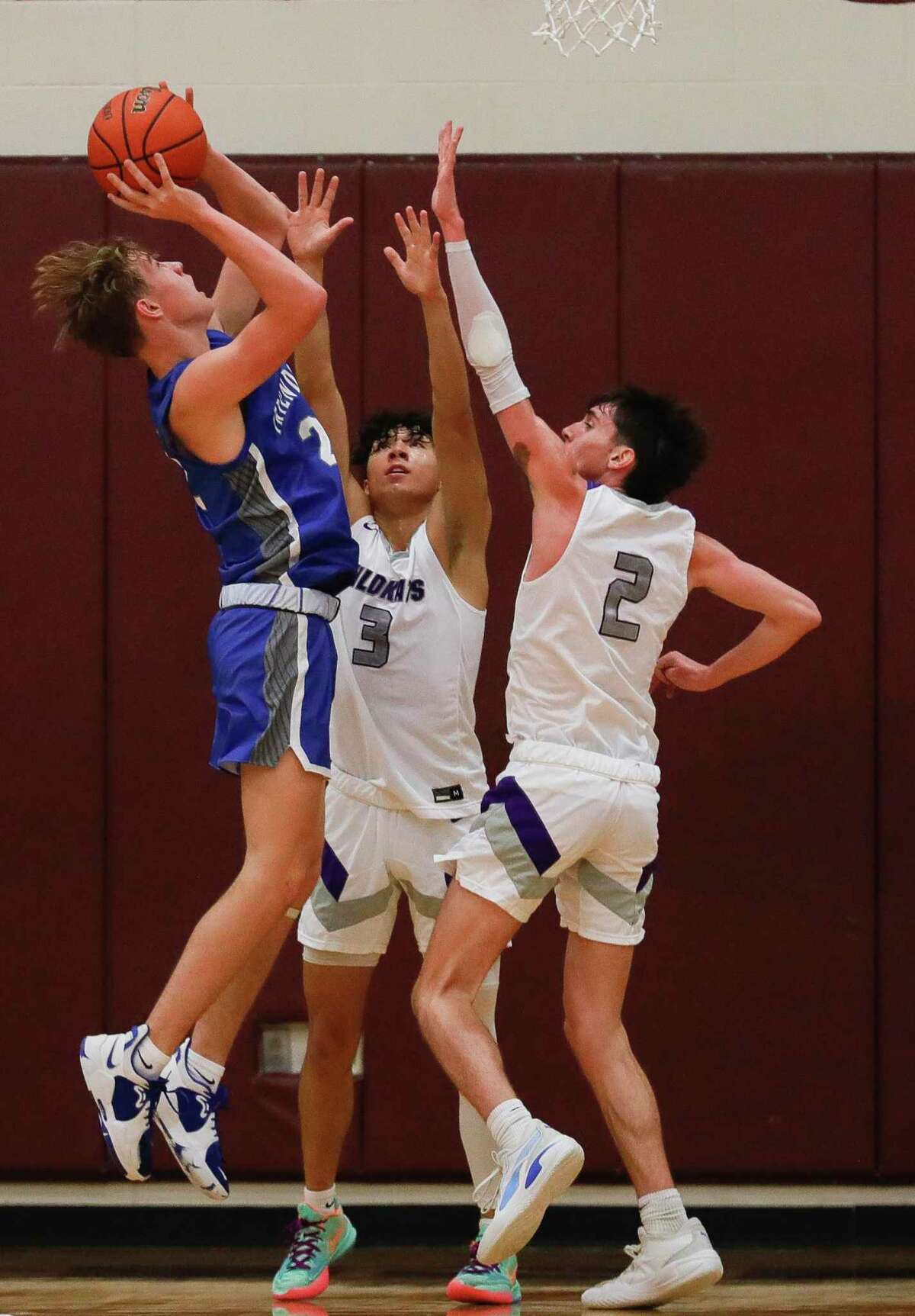 Friendswood’s T.J. Weatherly (22) goes up for a shot against Willis’ Derek Lagway, Jr. (3) and Tanner Davis (2) during the Doghouse Invitational tournament in November in Magnolia.