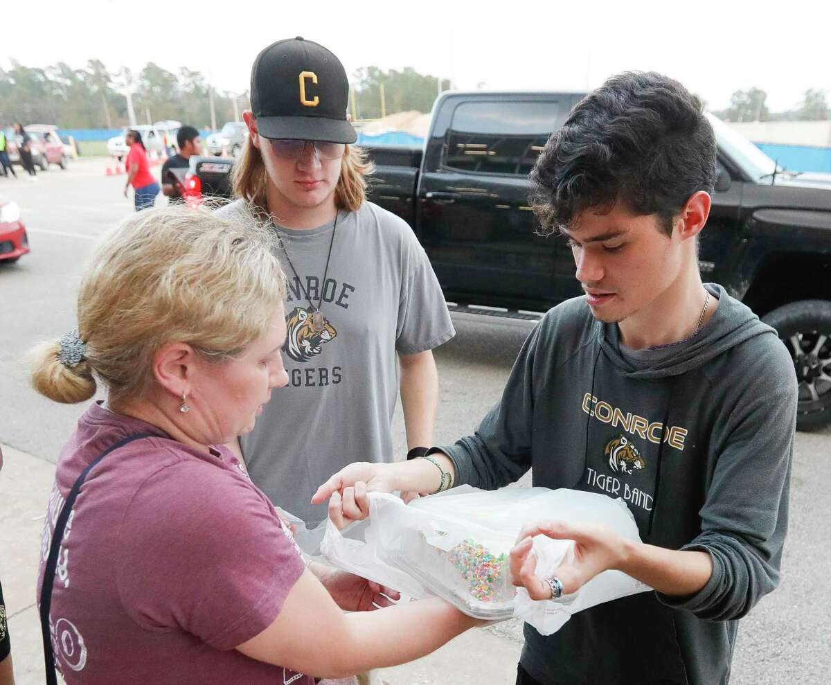 Lisa Michael, left, helps Triston Covell bag desserts as volunteers distribute meals for 200 families as part of H-E-B Feast of Sharing in partnership with the Montgomery County Food Bank at Conroe High School, Thursday, Dec. 9, 2021, in Conroe.