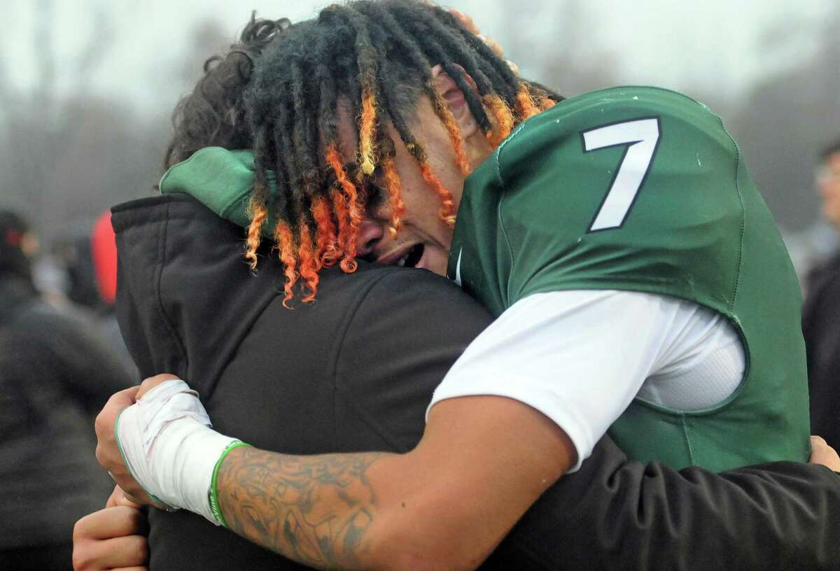 A Maloney player hugs Johnny Rosado, father of teammate Johnny Rosado after the team defeated Windsor in CIAC Class L state championship football action at Veterans Stadium in New Britain, Conn., on Saturday December 11, 2021.