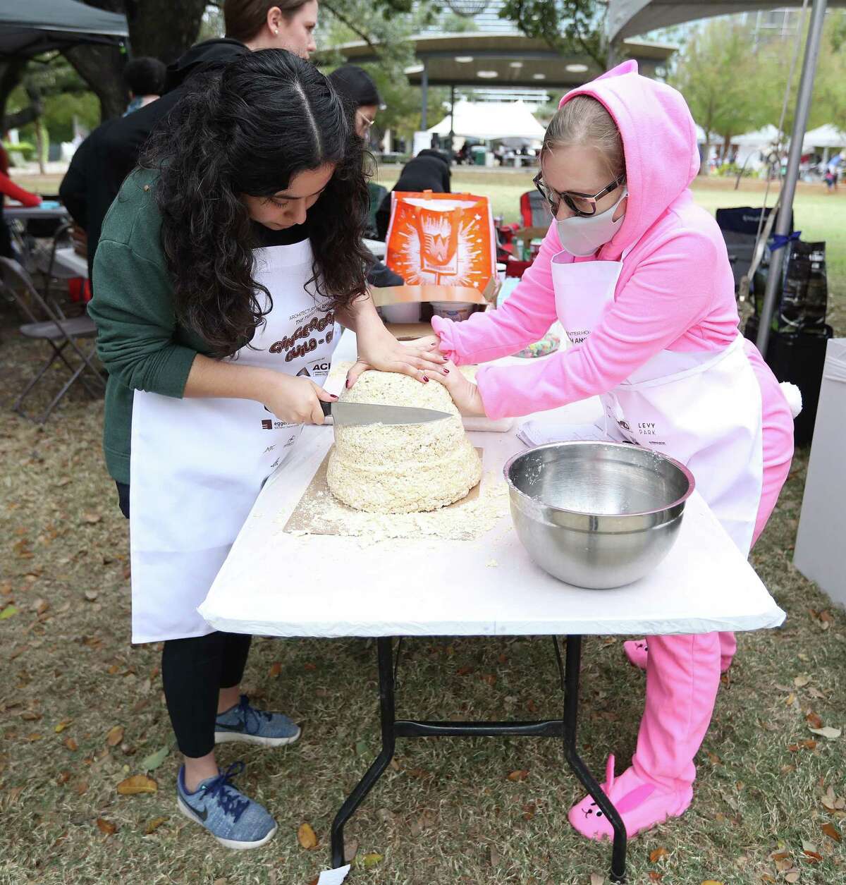 Dani Olivera, left, and Mikki Heckman, with Powers Brown Architecture, work on shaving down Rice Krispie treats into a form as Architecture Center Houston hosted the 12th annual gingerbread build-off at Levy Park, Saturday, Dec. 11, 2021 in Houston . Competing teams will create their masterpieces using 100 percent edible materials.
