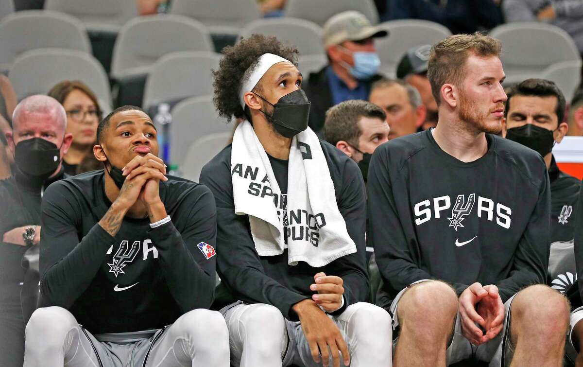 Spurs guard Derrick White, center, is masked up on the bench during a game last week.