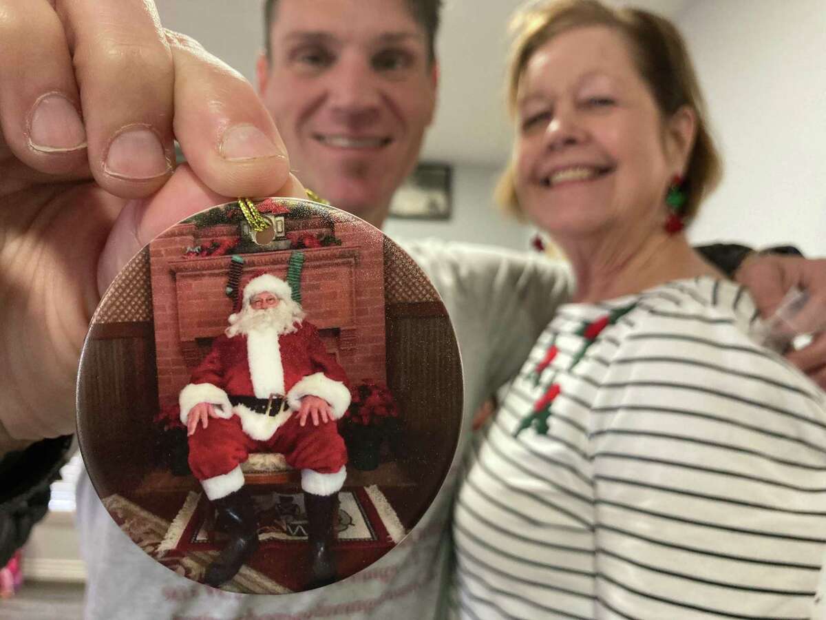 Adam Conrad, President of Heritage House, and Leslie Williams, a member of the board, hold up the ornament commemorating the 40+ years when Larry David served as the city’s Santa Claus.