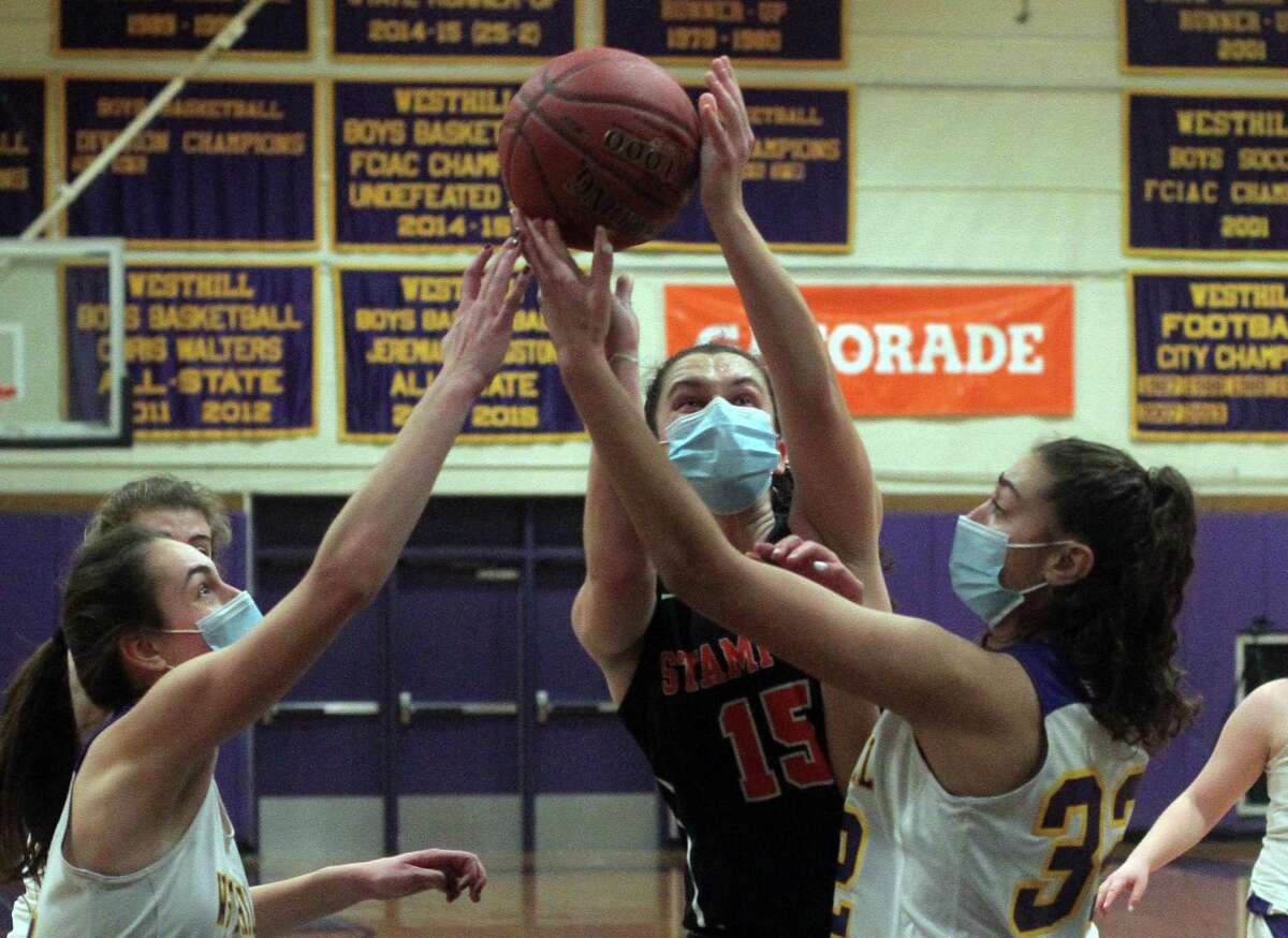 Stamford's Samantha Albert (15) looks for two points as Westhill's Olivia Conte (14), left, and Paige Hochadel (32) defend during girls basketball action in Stamford, Conn., on Saturday Feb. 20, 2021.