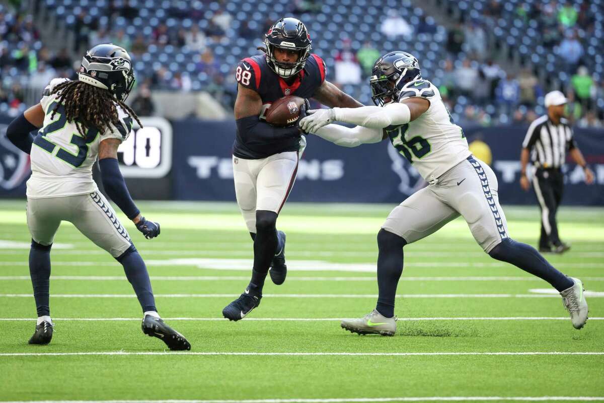 Houston Texans tight end Jordan Akins (88) runs the ball after a catch between Seattle Seahawks cornerback Sidney Jones IV (23) and linebacker Jordyn Brooks (56) during the fourth quarter of an NFL football game Sunday, Dec. 12, 2021 in Houston.