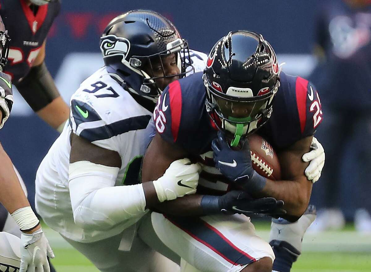 Seahawks defensive tackle Poona Ford (97) wraps up Texans running back Royce Freeman, who netted a mere 15 yards on 11 carries Sunday.