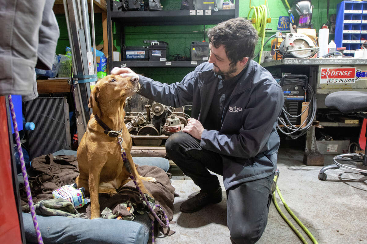 Mechanic Tyler Montobbio pats Ladybug, one of the shop dogs at Buslab.