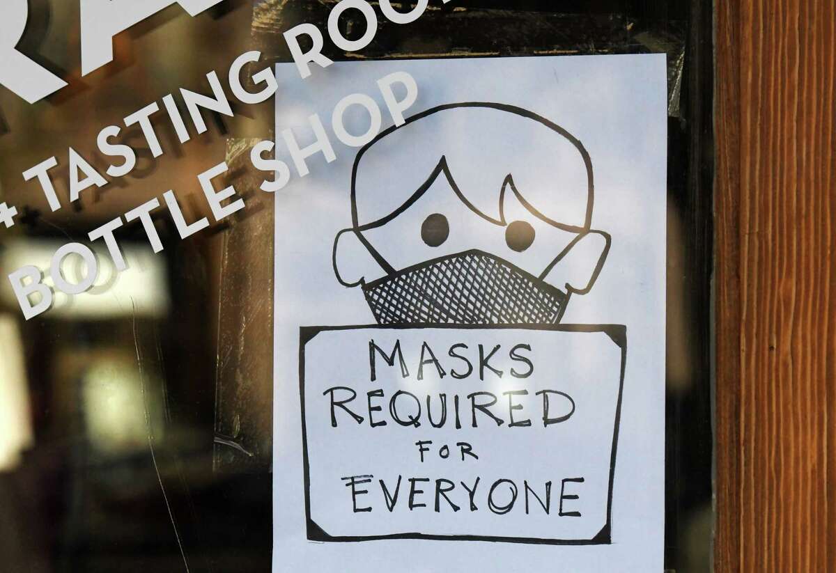A mask sign is posted on the door to 518 Craft on Monday, Dec. 13, 2021, in Troy, N.Y. The sign was made by a customer Sunday night in advance of New York state's new mask order that went into effect Monday. 518 Craft is a bar and tasting room for Shmaltz Brewing Company, which also houses Alias Coffee Roasters and Primo Botanica chocolate.