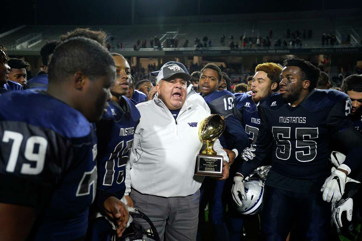 West Orange-Stark players crowd around head coach Cornel Thompson as he holds the trophy after they beat Wimberley in the Class 4A Division 2 state semifinal game at Legacy Stadium in Katy on Friday night. Photo taken Friday 12/15/17 Ryan Pelham/The Enterprise