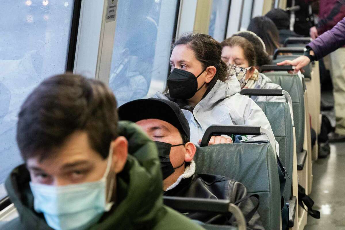 BART riders wear masks while riding a San Francisco-bound train on Monday. California has reinstated its mask mandate, which will run through Jan. 15.