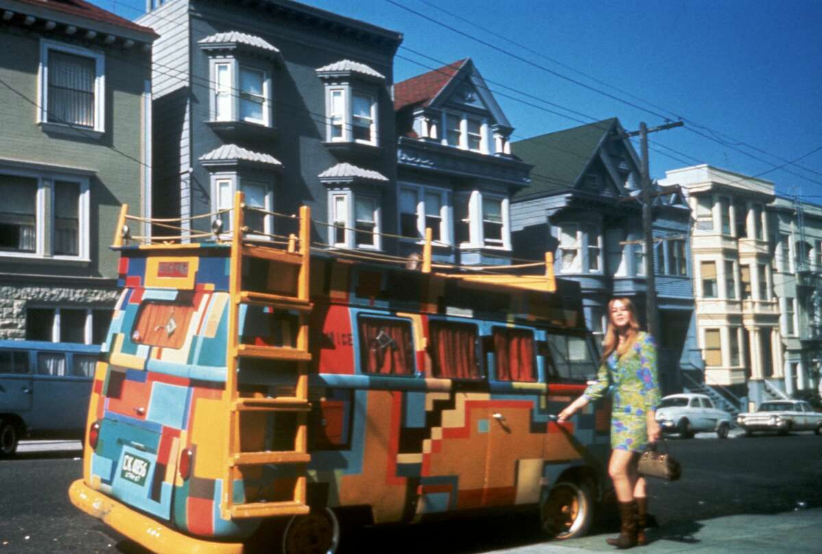 A woman stands next to a Volkswagen bus painted in a bold design in San Francisco in this photo dating back to July 1967.