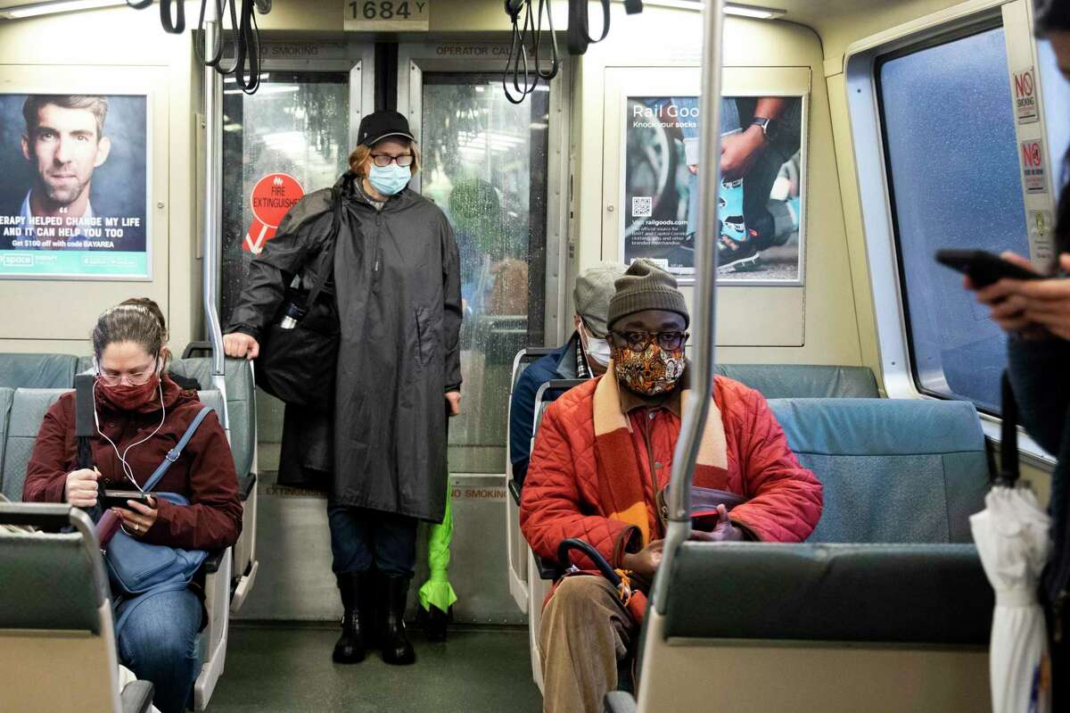 A BART rider wears a masks and raincoat while riding a San Francisco-bound train from Ashby Bart Station in Berkeley, Calif. Monday, Dec. 13, 2021.