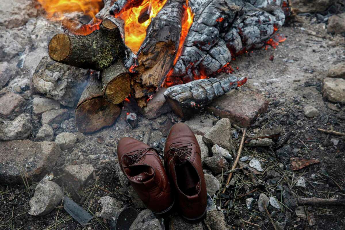 The shoes of a homeless camp residents are drying next to a fire after a rainstorm drenched the Marinship Park site in Sausalito.